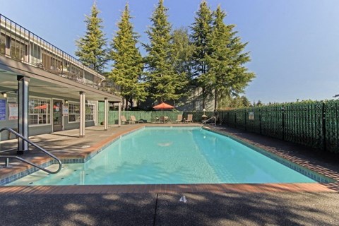 a swimming pool in front of a building with trees